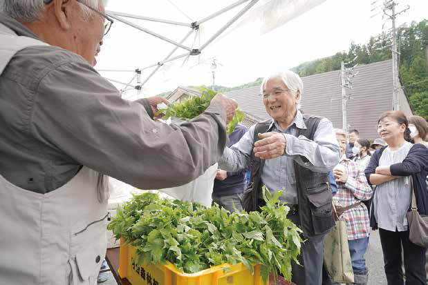 飛騨かわい山菜市で山菜を受け取る様子
