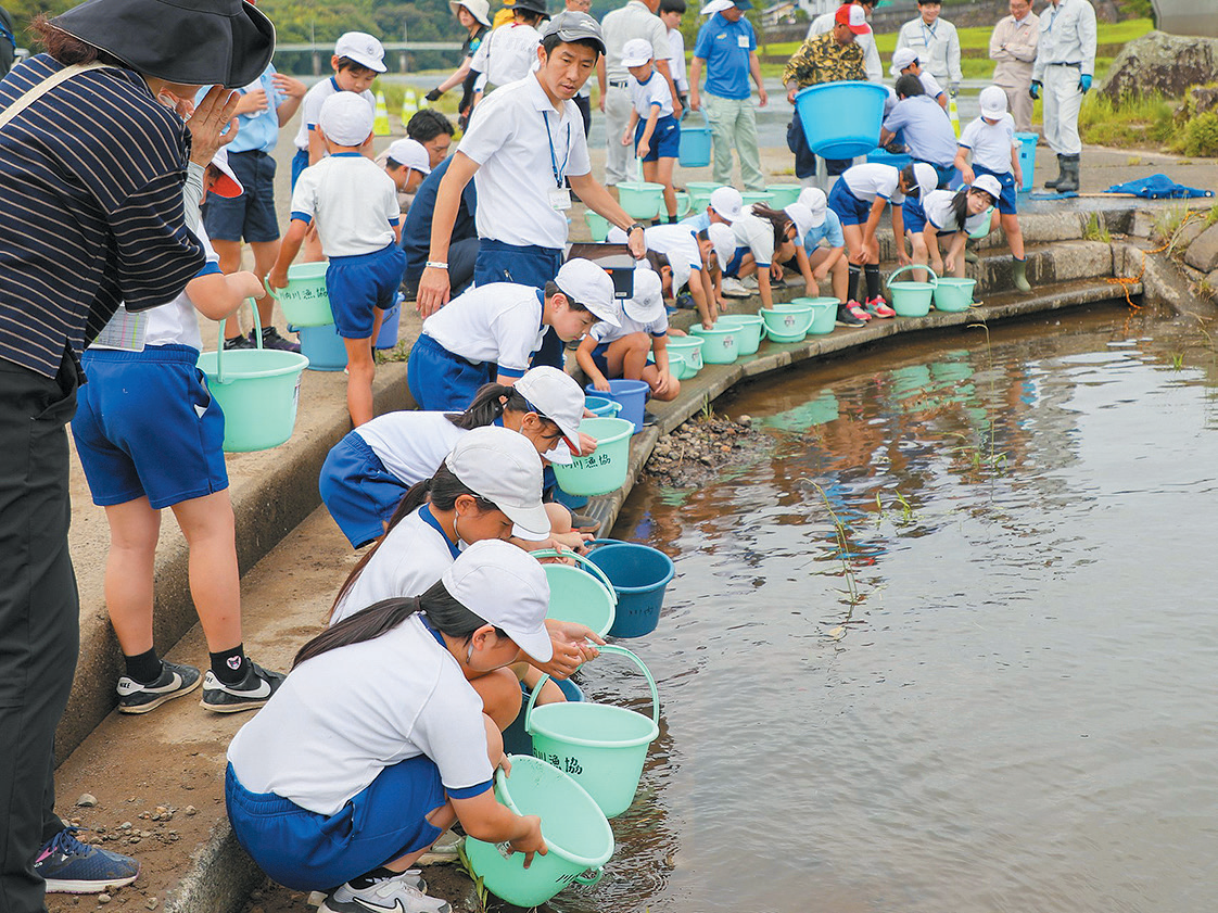 川の生き物と触れ合い、楽しく放流を行う児童たち